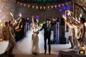 Bride and groom entering the reception venue surrounded by guests holding glowing fireworks in Moselle, creating a warm and festive atmosphere.